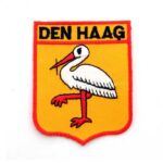 Foto van een badge van Den Haag met de afbeelding van een Ooievaar.